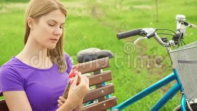在公园热的时候，女人在手机上使用便携式呼吸机。 用小风扇冷却